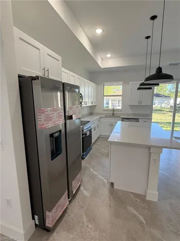 Kitchen with appliances with stainless steel finishes, white cabinetry, a kitchen island, pendant lighting, and recessed lighting