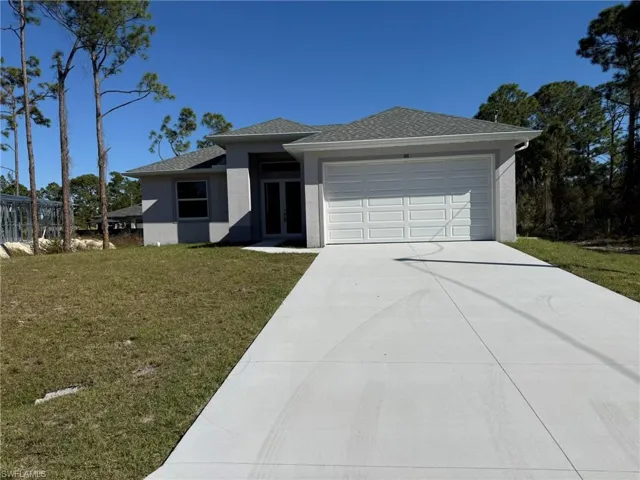 View of front of property with a front yard, stucco siding, driveway, a shingled roof, and a garage