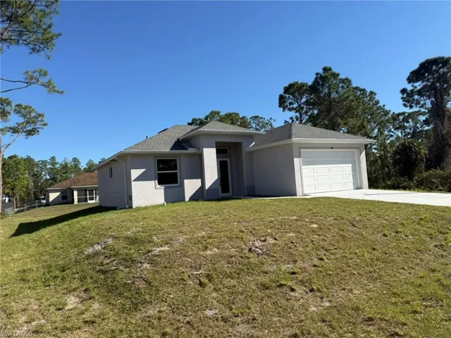 View of front facade with stucco siding, an attached garage, a front yard, and driveway