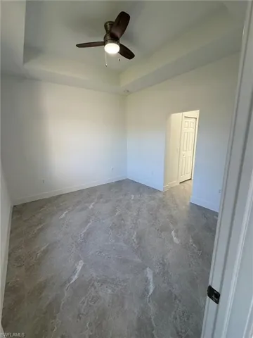 Empty room featuring a raised ceiling and a ceiling fan