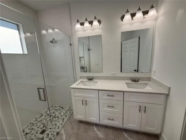 Full bathroom featuring double vanity and a shower stall