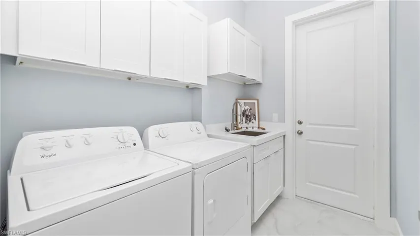 Laundry area with cabinet space, washing machine and clothes dryer, and light marble finish flooring