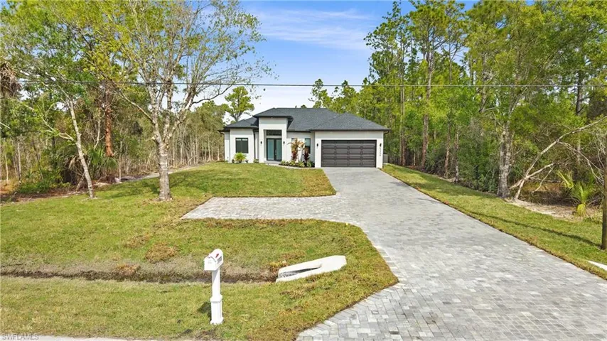 View of front of home with an attached garage, a front lawn, decorative driveway, and stucco siding