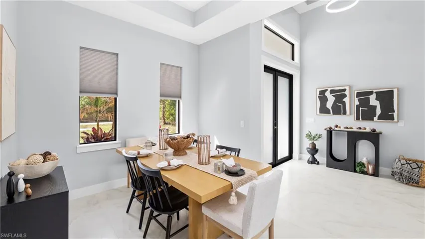 Dining area with light marble finish floors and a high ceiling
