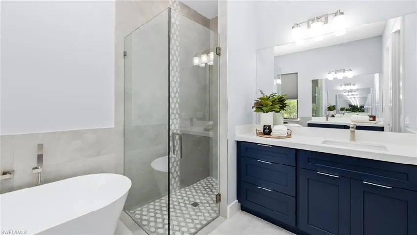 Full bath featuring a stall shower, vanity, a soaking tub, and tile walls
