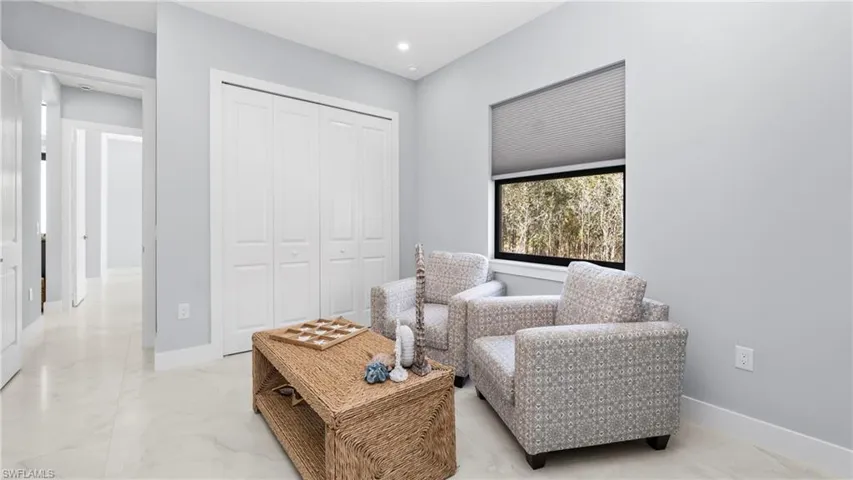 Living area with light marble finish flooring and recessed lighting