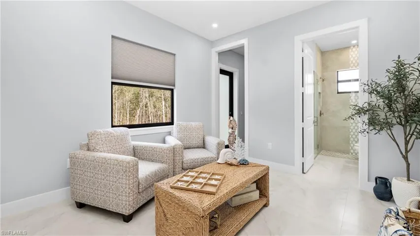 Living area featuring baseboards and light marble finish flooring