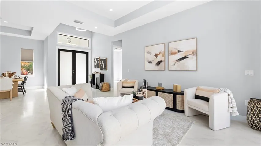 Living room with french doors, a raised ceiling, and recessed lighting