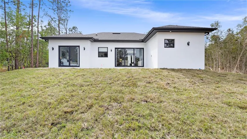 Back of property with stucco siding and a yard