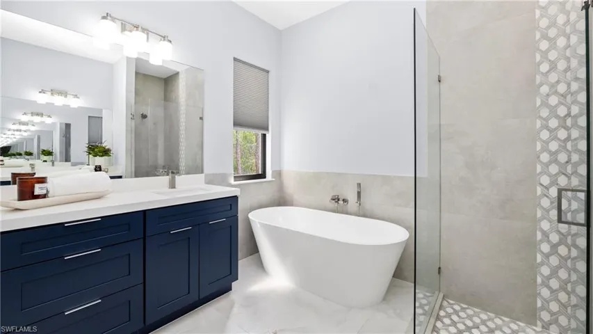 Bathroom with vanity, a stall shower, a soaking tub, tile walls, and light marble finish floors
