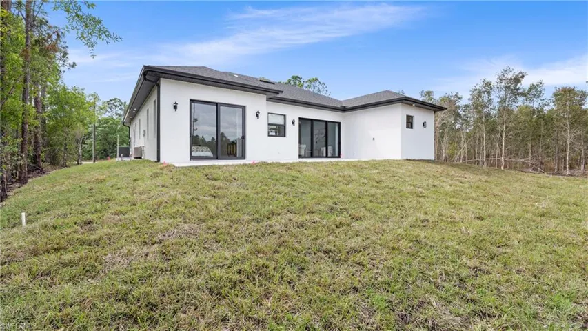 Back of property with stucco siding and a lawn