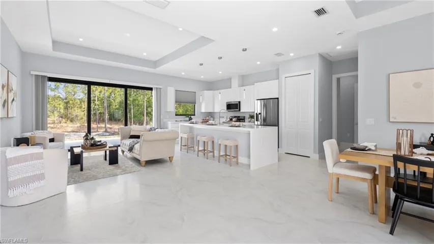 Living room with a tray ceiling, light marble finish floors, and recessed lighting