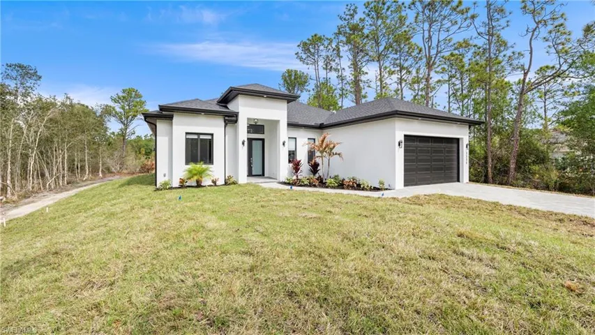 Prairie-style home with a garage, a front lawn, driveway, and stucco siding