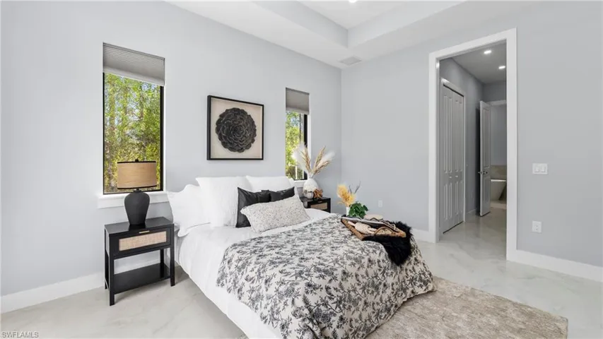 Bedroom with connected bathroom and recessed lighting
