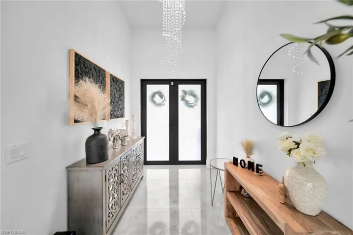 Foyer entrance featuring french doors, a chandelier, and light tile patterned floors