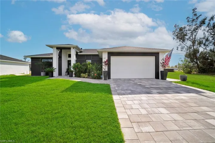 Prairie-style house with decorative driveway, a front lawn, a garage, and stucco siding