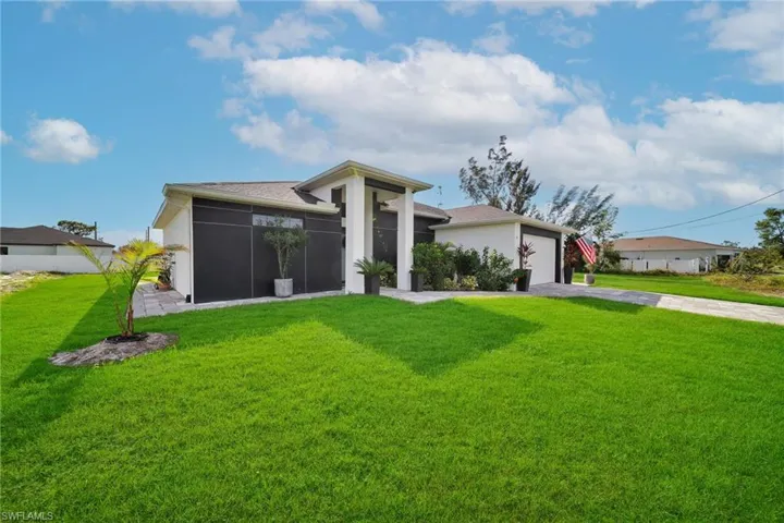View of front of home with concrete driveway, a front lawn, stucco siding, an attached garage, and a sunroom