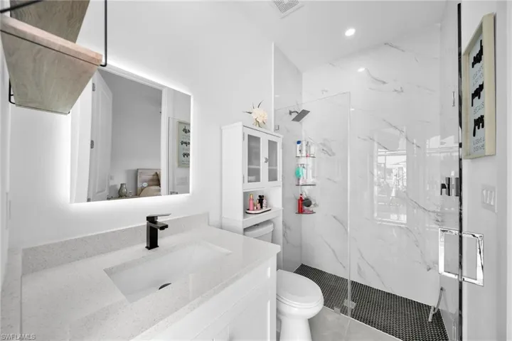 Ensuite bathroom featuring a marble finish shower, vanity, and recessed lighting