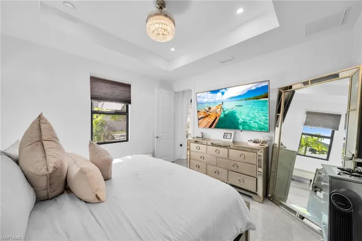 Bedroom featuring a raised ceiling, multiple windows, recessed lighting, and light tile patterned flooring