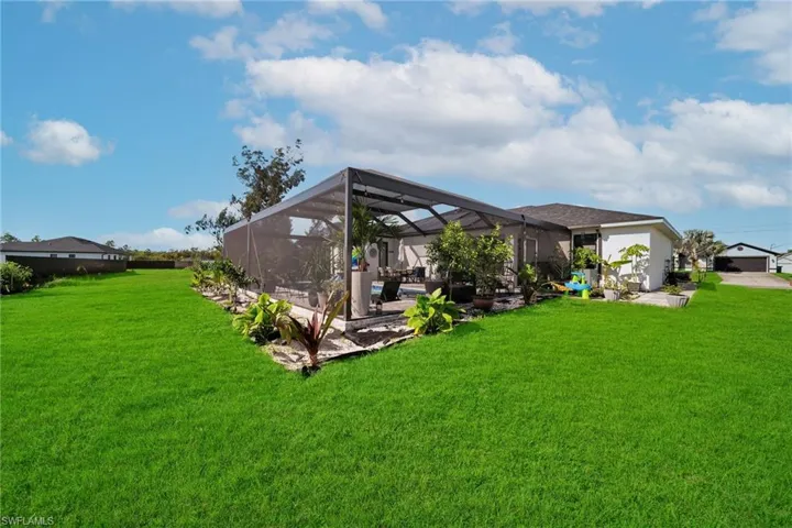 View of green lawn featuring a patio and a lanai