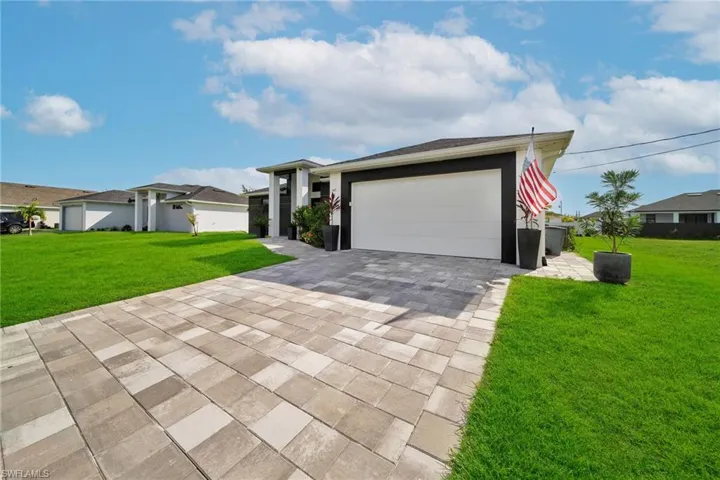 View of front of house featuring a front yard, decorative driveway, and an attached garage