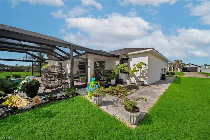 Rear view of house with stucco siding, a yard, a patio area, and glass enclosure