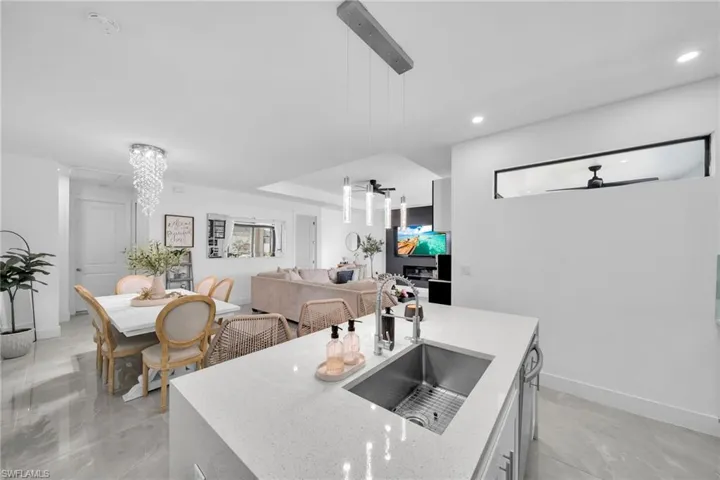 Kitchen featuring light stone counters, hanging light fixtures, open floor plan, recessed lighting, and a ceiling fan