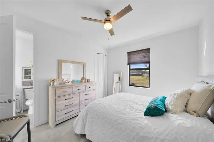Bedroom featuring connected bathroom, ceiling fan, a closet, and light tile patterned floors