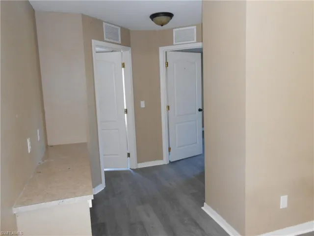 Hall featuring dark wood-style flooring and baseboards