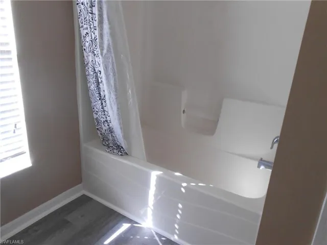 Full bathroom featuring shower / bath combo and dark wood finished floors