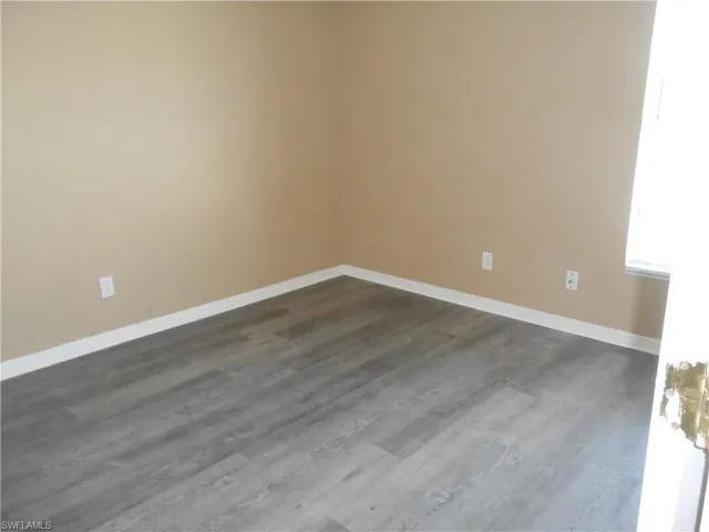 Unfurnished room with dark wood-style flooring and baseboards