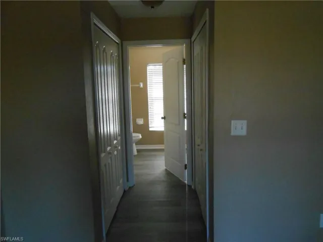 Corridor featuring baseboards and dark wood-style flooring