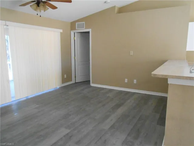 Unfurnished dining area featuring lofted ceiling, dark wood-style flooring, and a ceiling fan