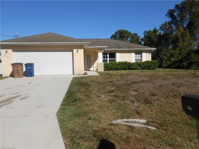 Single story home with stucco siding, a front yard, driveway, and a garage