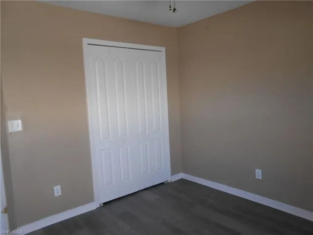 Unfurnished bedroom with dark wood finished floors and a closet