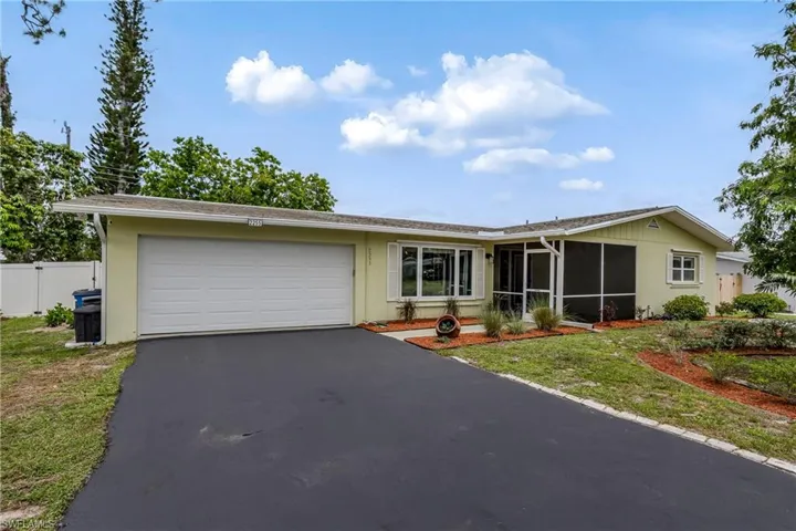 Single story home featuring driveway, an attached garage, and a sunroom