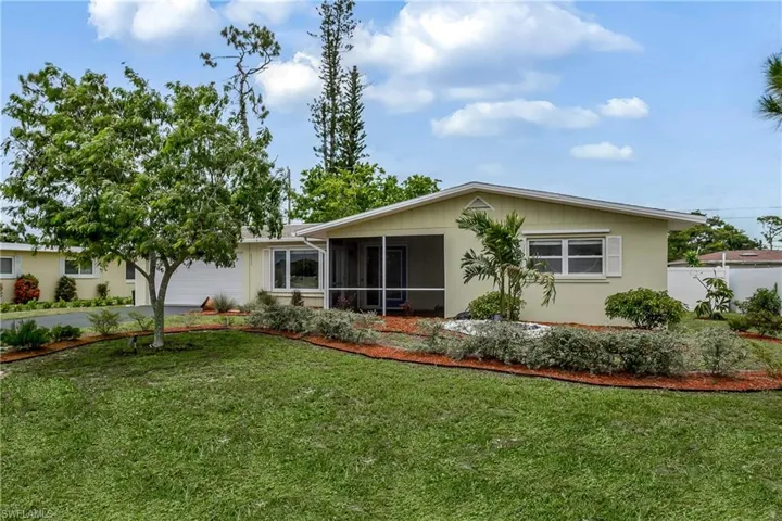 Front view of property featuring a sunroom, a garage, a lawn, and driveway
