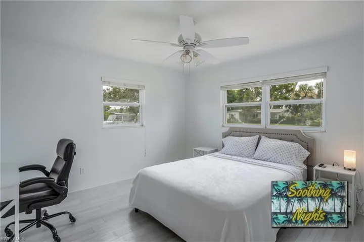 Bedroom featuring light wood finished floors, an office area, and a ceiling fan