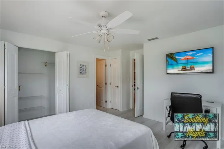 Bedroom featuring an office area, light wood-style floors, a ceiling fan, and a closet