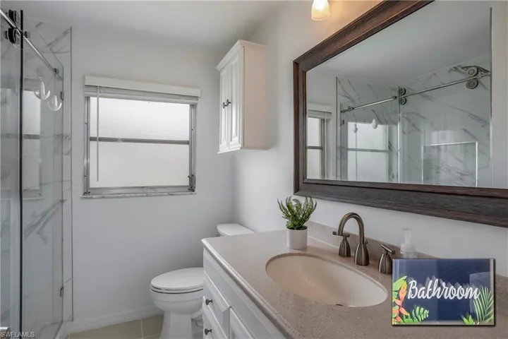Bathroom with vanity, plenty of natural light, and a marble finish shower
