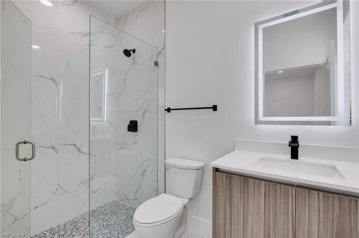 Bathroom featuring a marble finish shower and vanity