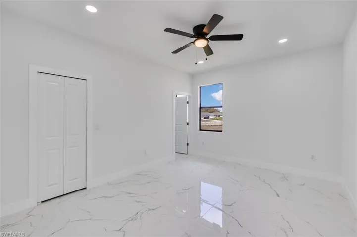 Unfurnished bedroom with recessed lighting, a ceiling fan, a closet, and light marble finish floors