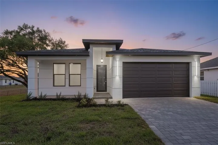 View of front of property with decorative driveway, an attached garage, and stucco siding