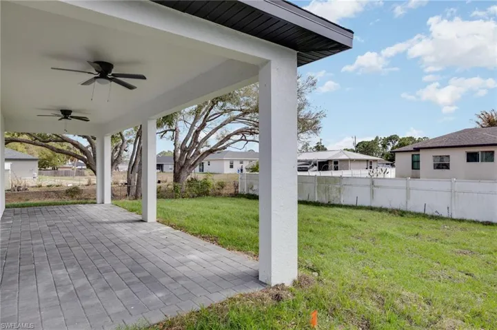 Fenced backyard with ceiling fan, a patio area, and a residential view