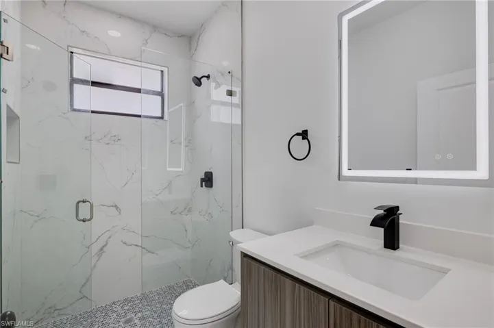 Bathroom with vanity and a marble finish shower