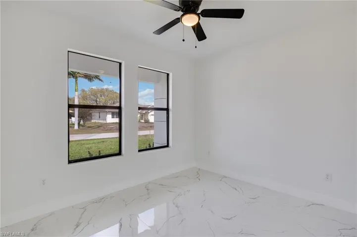 Spare room featuring light marble finish flooring and ceiling fan