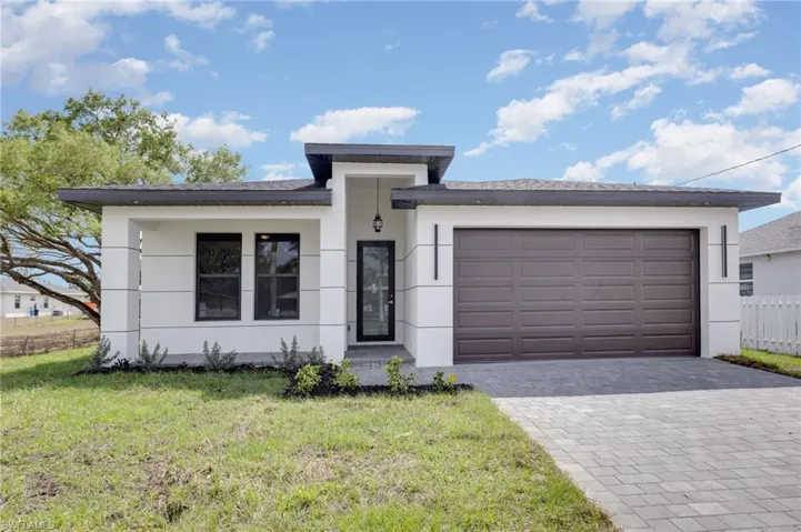 View of front facade with decorative driveway, stucco siding, and a garage