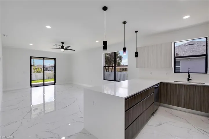 Kitchen with hanging light fixtures, a peninsula, light marble finish flooring, open floor plan, and light stone countertops
