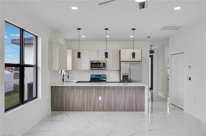 Kitchen with a peninsula, modern cabinets, pendant lighting, and stainless steel appliances