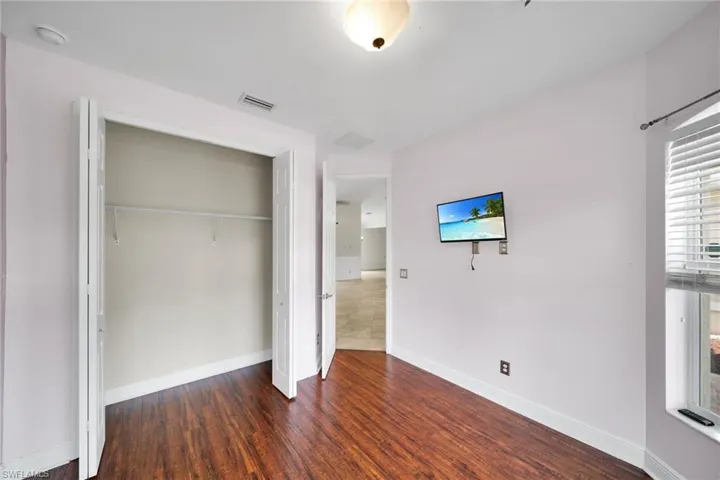 Unfurnished bedroom featuring wood finished floors, a closet, and baseboards